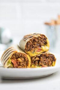 A plate of three vegan cheeseburger wraps halved and on a plate.