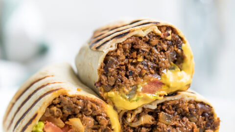 A plate of three vegan cheeseburger wraps halved and on a plate.