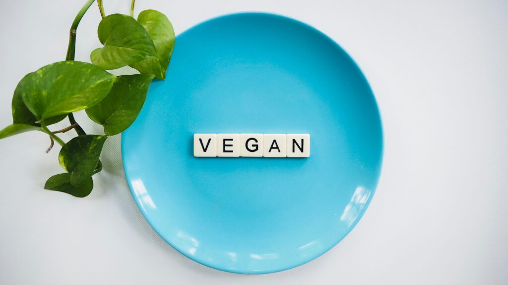 A blue plate with tiles on it that spell out vegan.