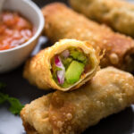 vegan avocado egg rolls with a bit missing out of one.