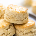 three flakey vegan buttermilk biscuits stacked on a plate.
