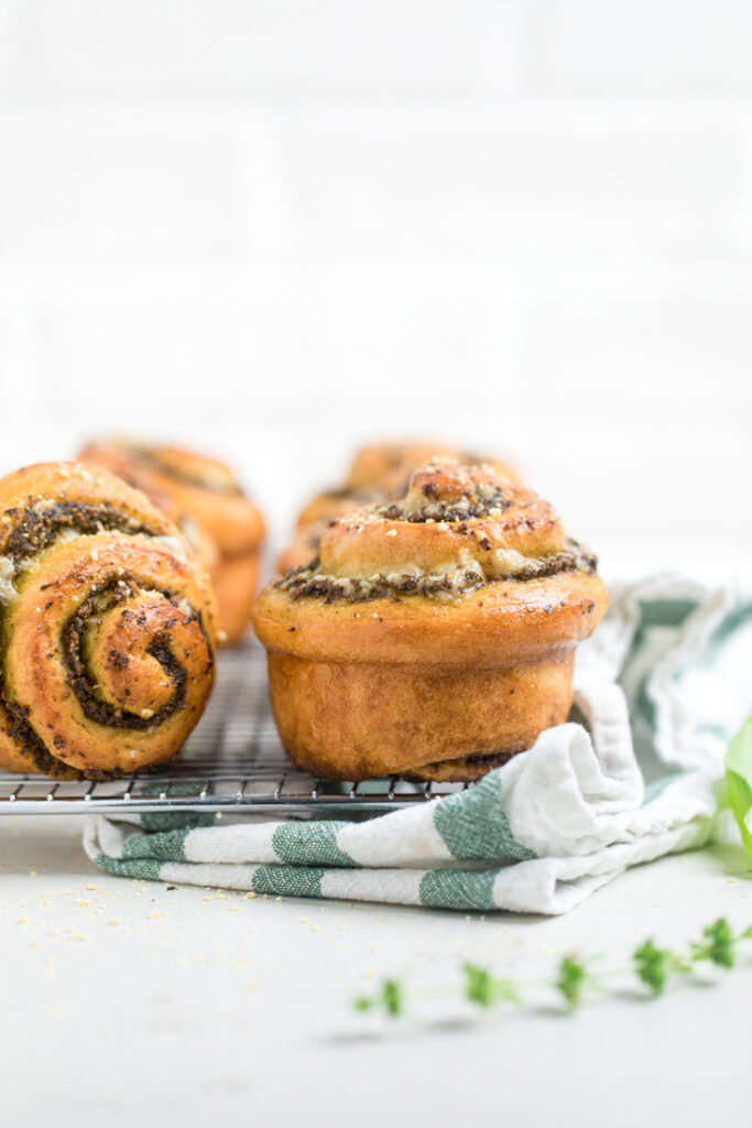 Two golden brown vegan pesto rolls, one laying on its side.