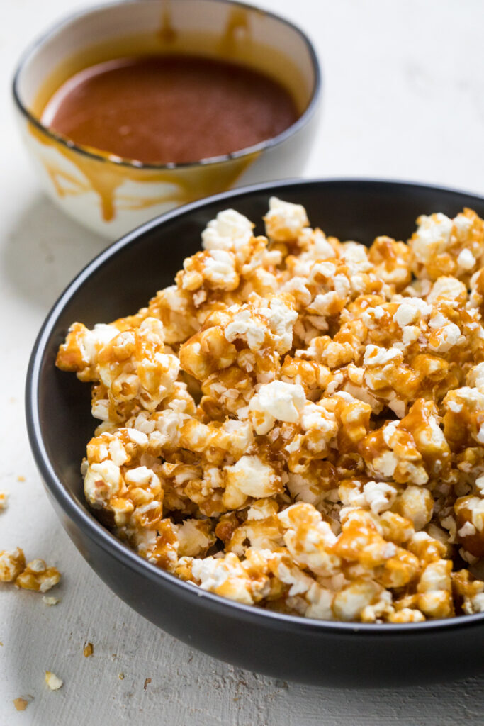 A bowl of vegan caramel popcorn with extra caramel drizzled on top.