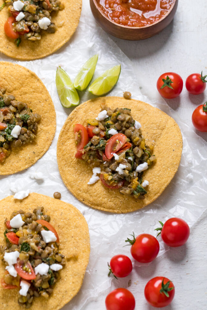 A table filled with vegan lentil tostadas with fresh tomatoes and vegan feta.