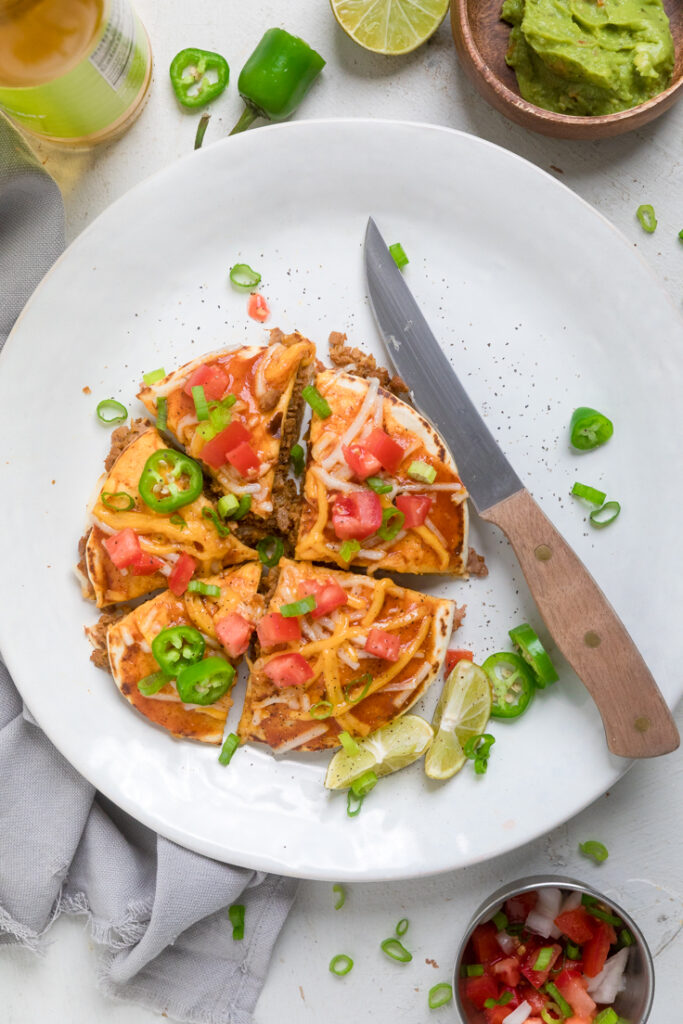 A plate of vegan mexican pizza sliced with fresh tomatoes and jalapenos. 