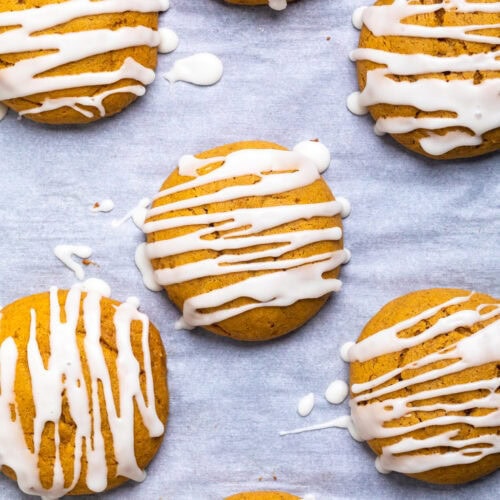 Vegan pumpkin cookies with glaze on parchment paper.