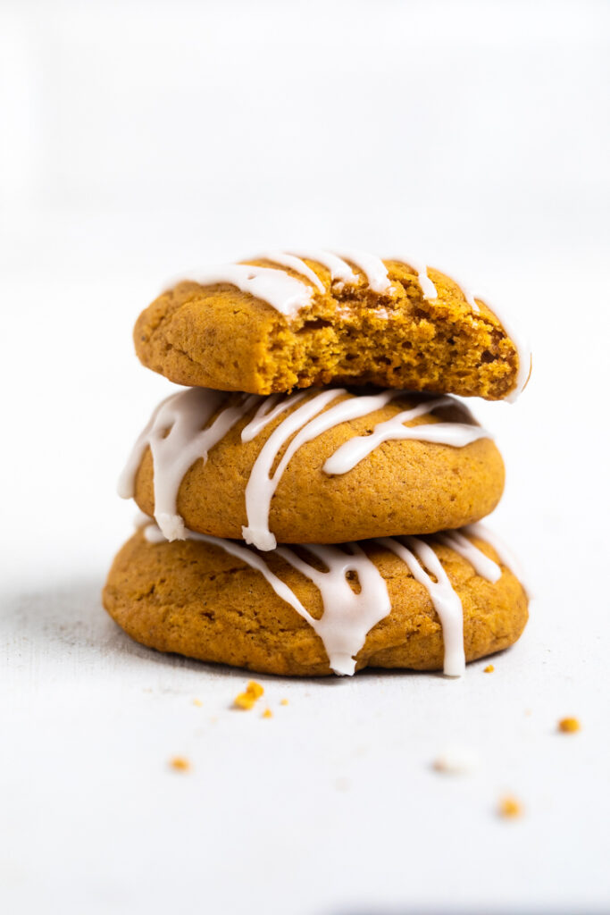 A stack of vegan pumpkin cookies with a bite taken out of the top one. 