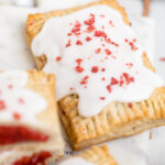 A vegan strawberry pop tart topped with frosting and crushed dried strawberries.