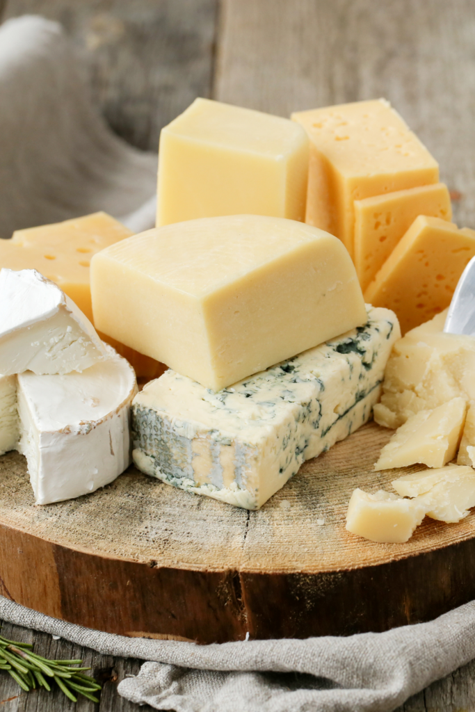 An assortment of cheese on a wooden board.