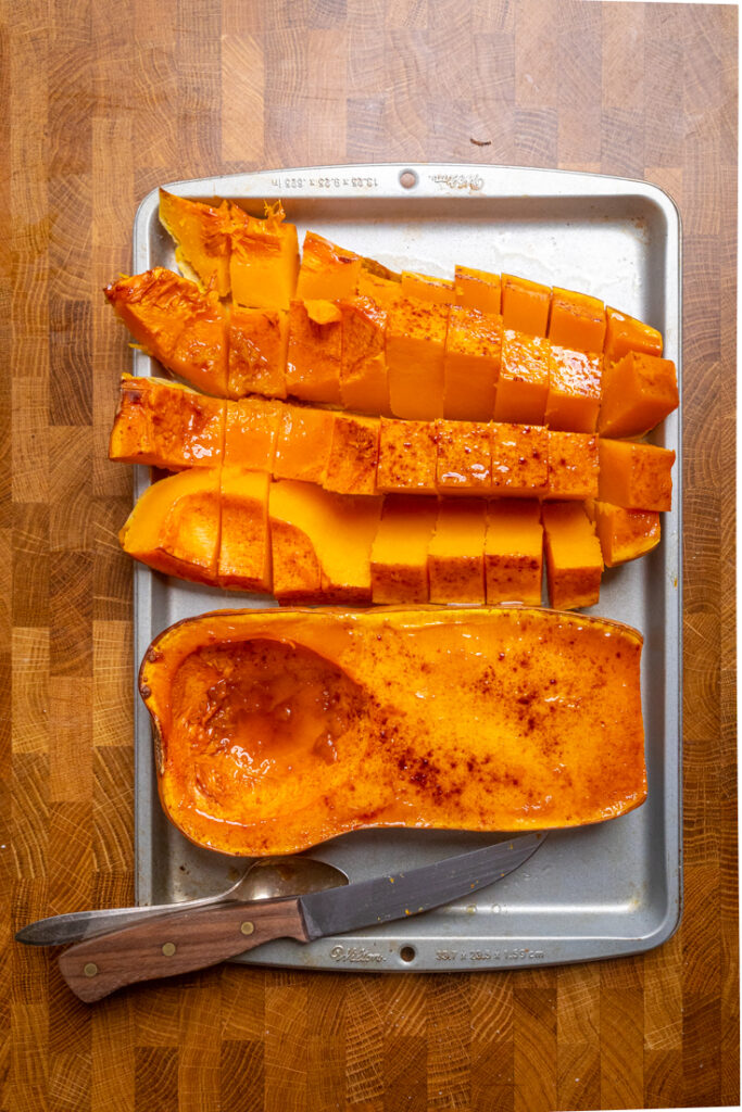 Two halves of cooked roasted butternut squash, one cut into cubes.