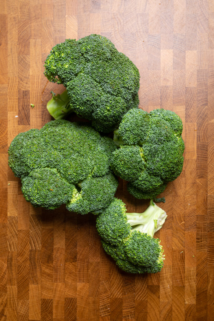 Four Heads of broccoli on a table.