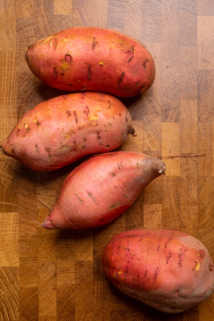Uncut and uncooked Sweet potatoes on a table.