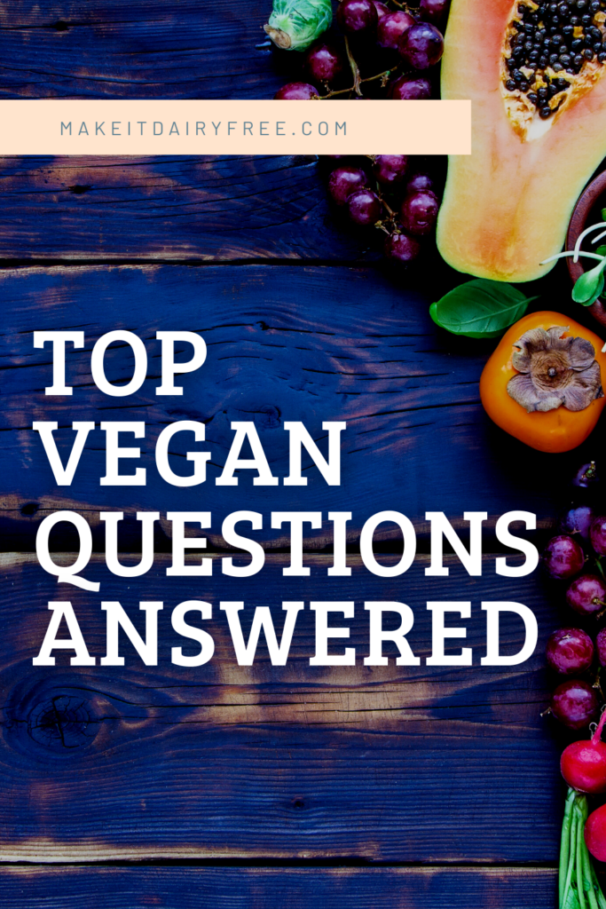 The words Top Vegan Questions Answered on a blue tray with fresh fruit and vegetables.