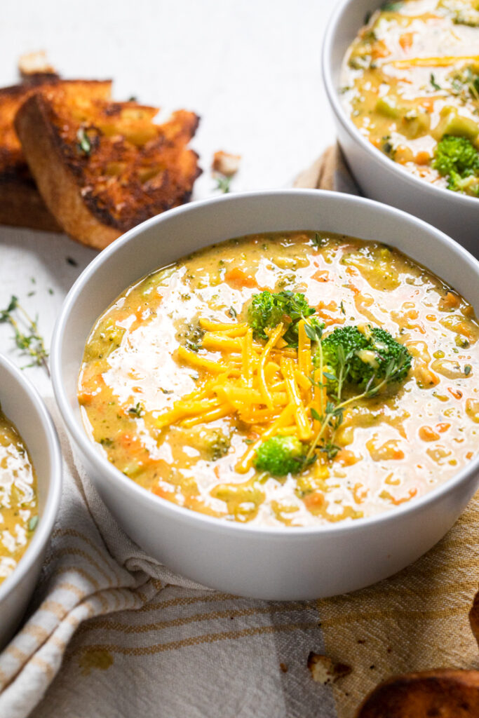 A white bowl of vegan broccoli and cheese soup.