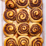 A tray of cooked unfrosted vegan brown butter pecan cinnamon rolls.