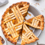 A vegan caramel apple pie when one sliced removed and two other pieces sliced.