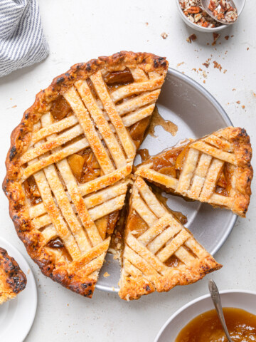 A vegan caramel apple pie when one sliced removed and two other pieces sliced.
