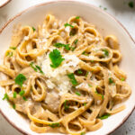A white bowl of vegan one pot creamy garlic parmesan pasta topped with fresh parsley.