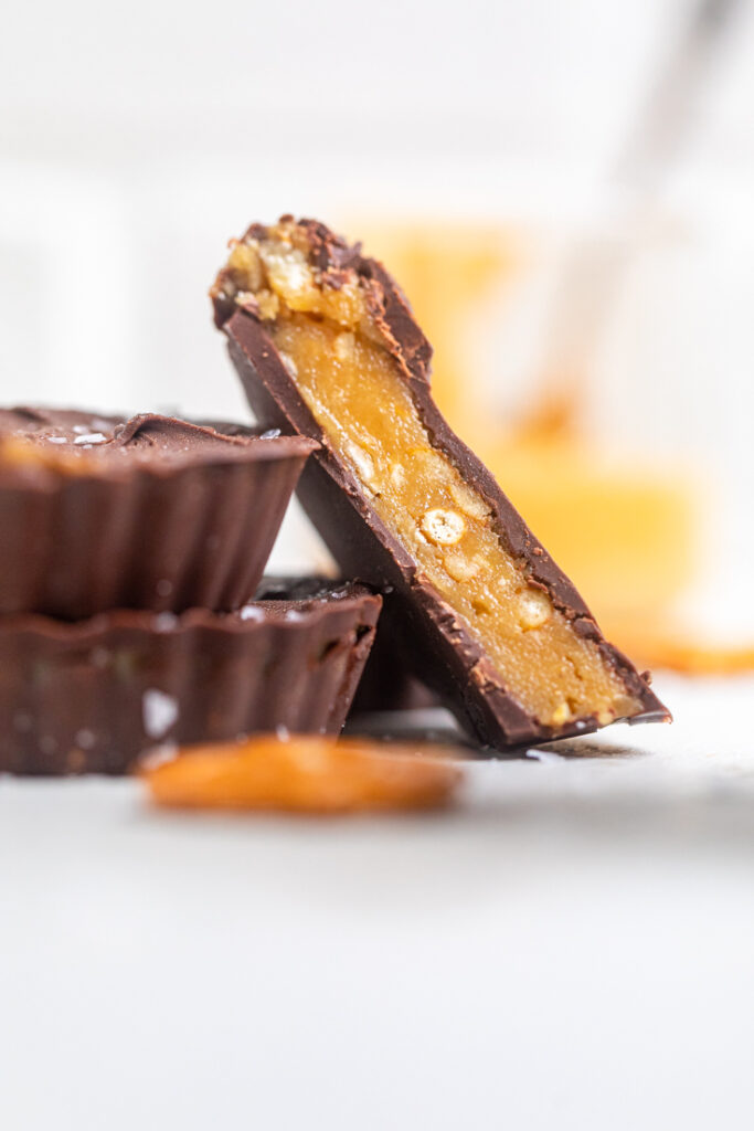 A vegan peanut butter pretzel cup halved to show creamy and crunchy filling.
