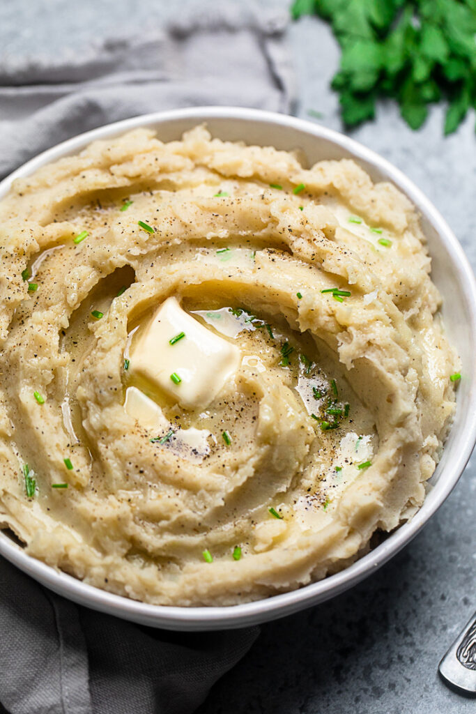 One pot 30 minute vegan mashed potatoes and gravy inside a white bowl with a pat of butter.