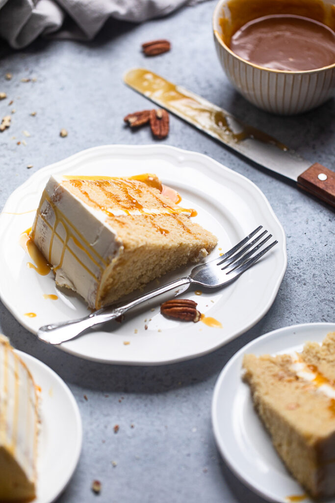 A thick slice of vegan caramel cake on a plate laying flat. 