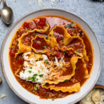 A white and gray bowl of Vegan Lasagna Soup topped with vegan ricotta.