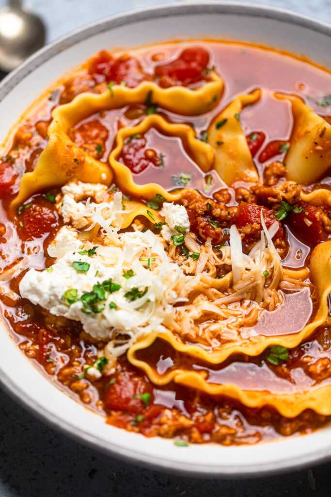 A bowl of vegan lasagna soup with a dollop of vegan ricotta. 