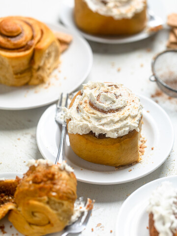 One frosted Vegan Sweet Potato Pie Cinnamon Roll on a white plate.