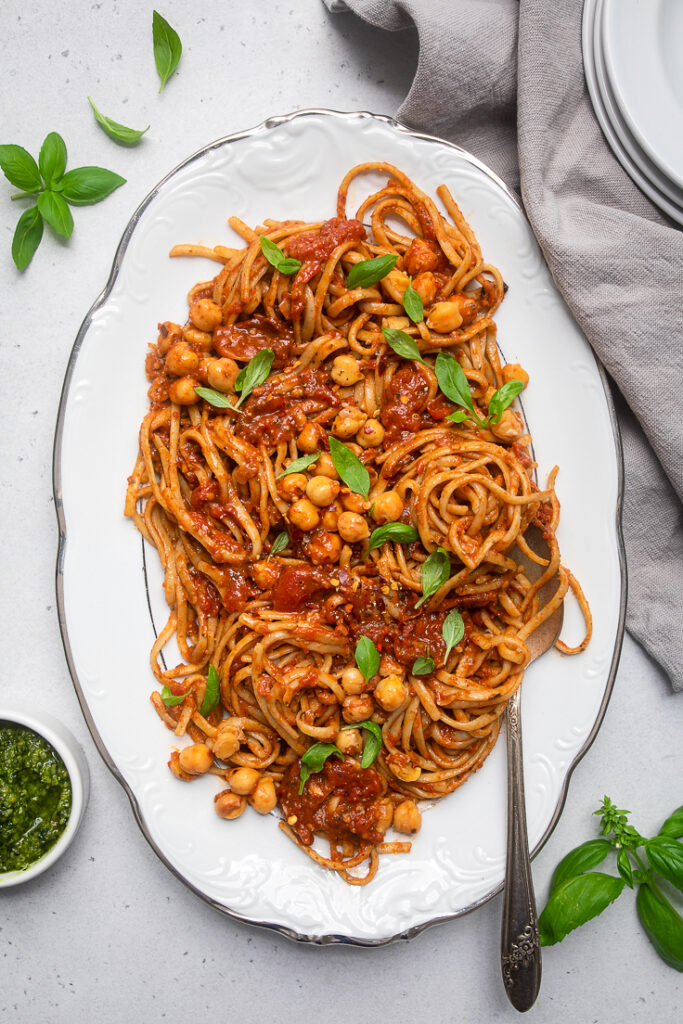 A plate of Vegan Spicy Chickpeas with Tomato Basil Pasta with fresh basil.