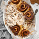 A dish of Vegan Gingerbread Cinnamon Rolls with some frosted.