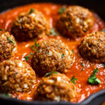 A dish of spaghetti sauce topped with Vegan TVP Meatballs.