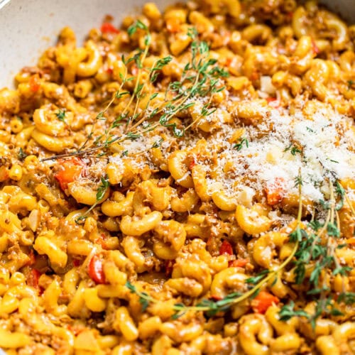 A serving of Vegan cheesy hamburger helper topped with vegan parmesan and fresh thyme.