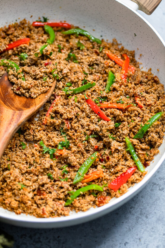 Vegan sunflower seed taco meat cooked in a bowl and topped with fresh peppers.