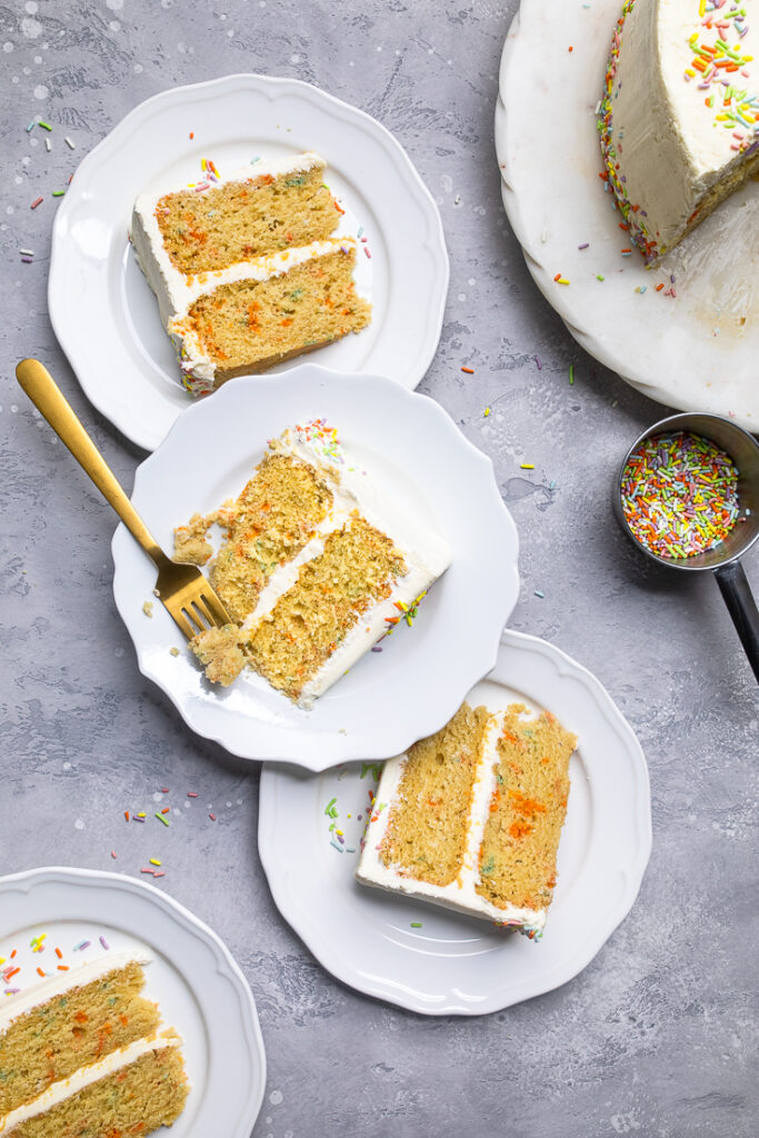 Three plates of vegan vanilla birthday cake slices laying flat.