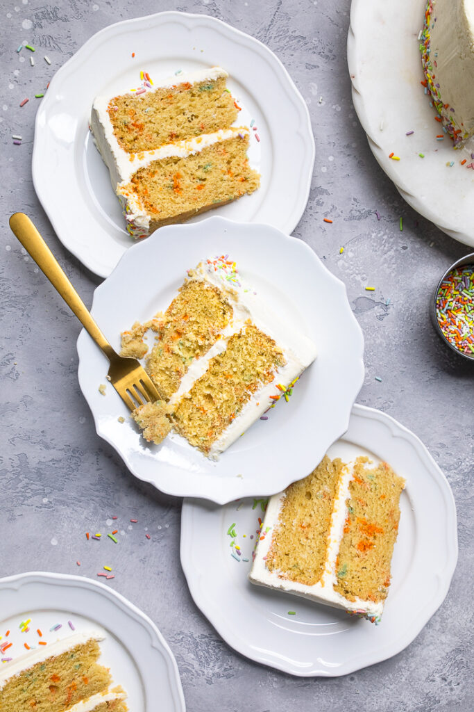 Three slices of vegan vanilla birthday cake on separate plates. 