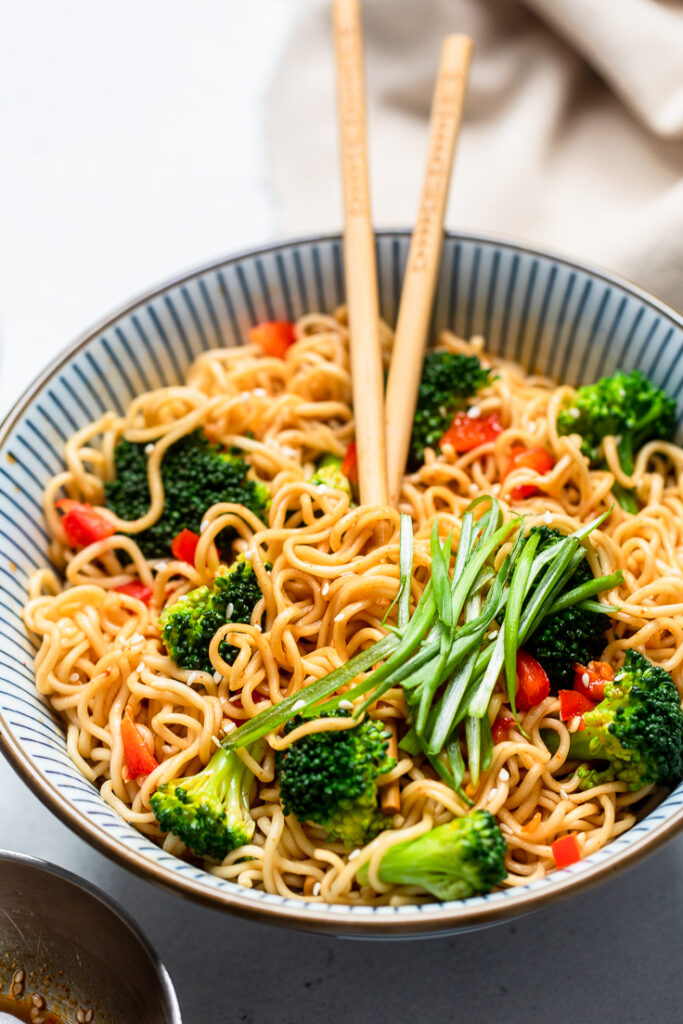 vegan ramen noodles with broccoli and red peppers, topped with green onions.