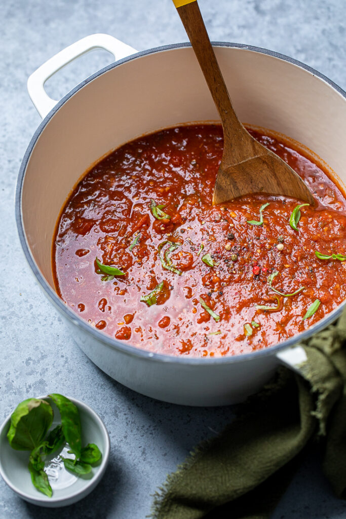 A spoon stirring a pot of homemade vegan spaghetti sauce.