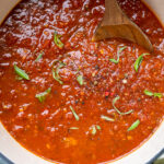 Homemade vegan spaghetti sauce in a pot topped with fresh basil.