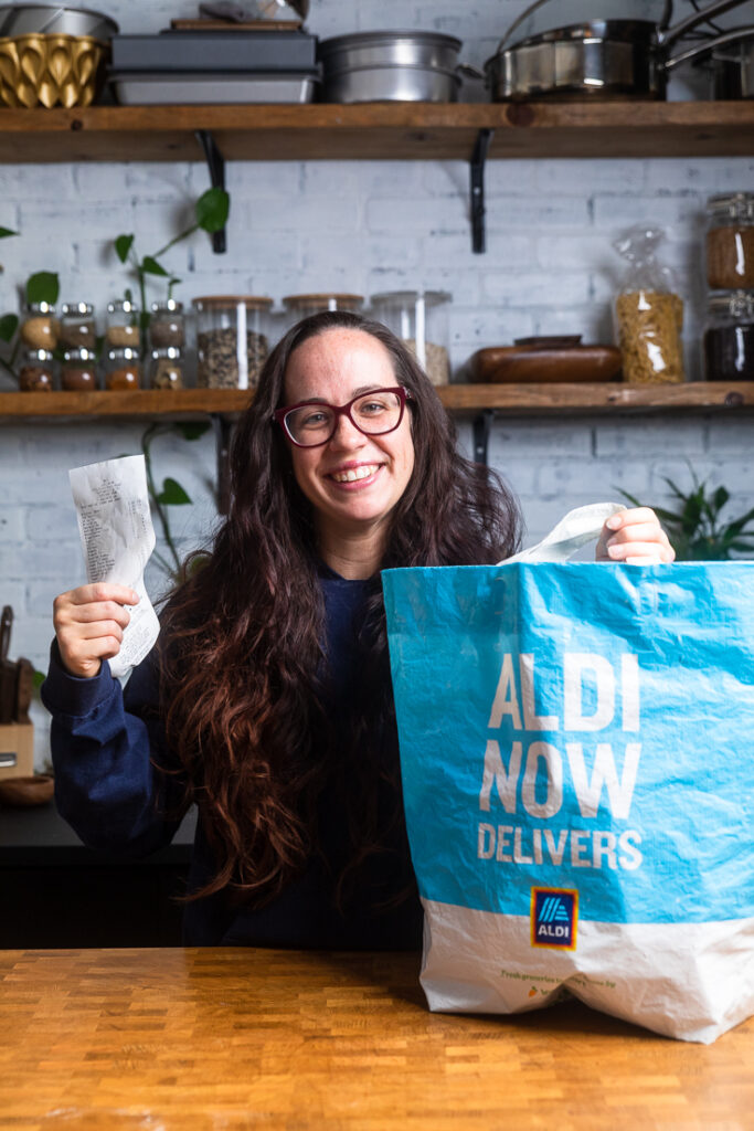 A woman holding up an Aldi\'s bag and receipt.