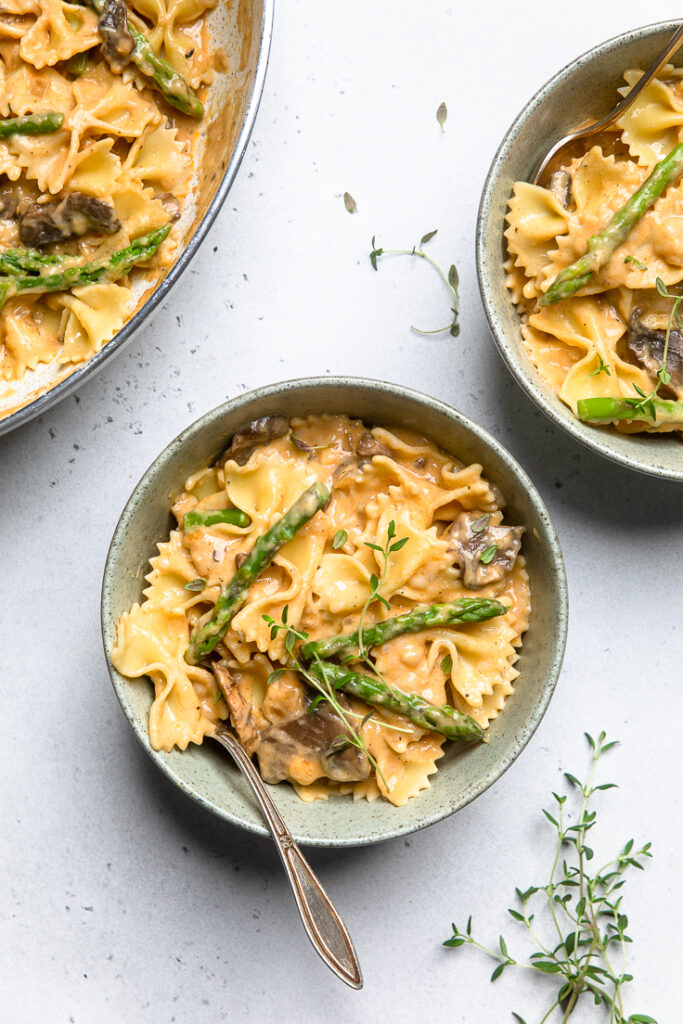 Three bowl of vegan creamy mushroom asparagus pasta.