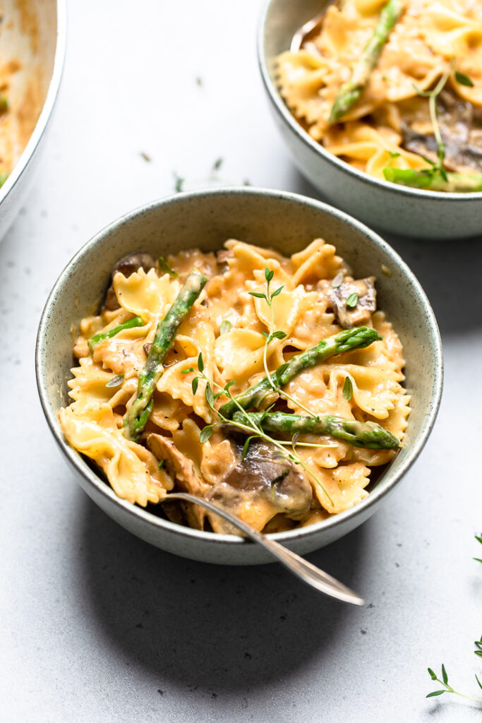 A serving bowl of vegan creamy mushroom  and asparagus pasta.