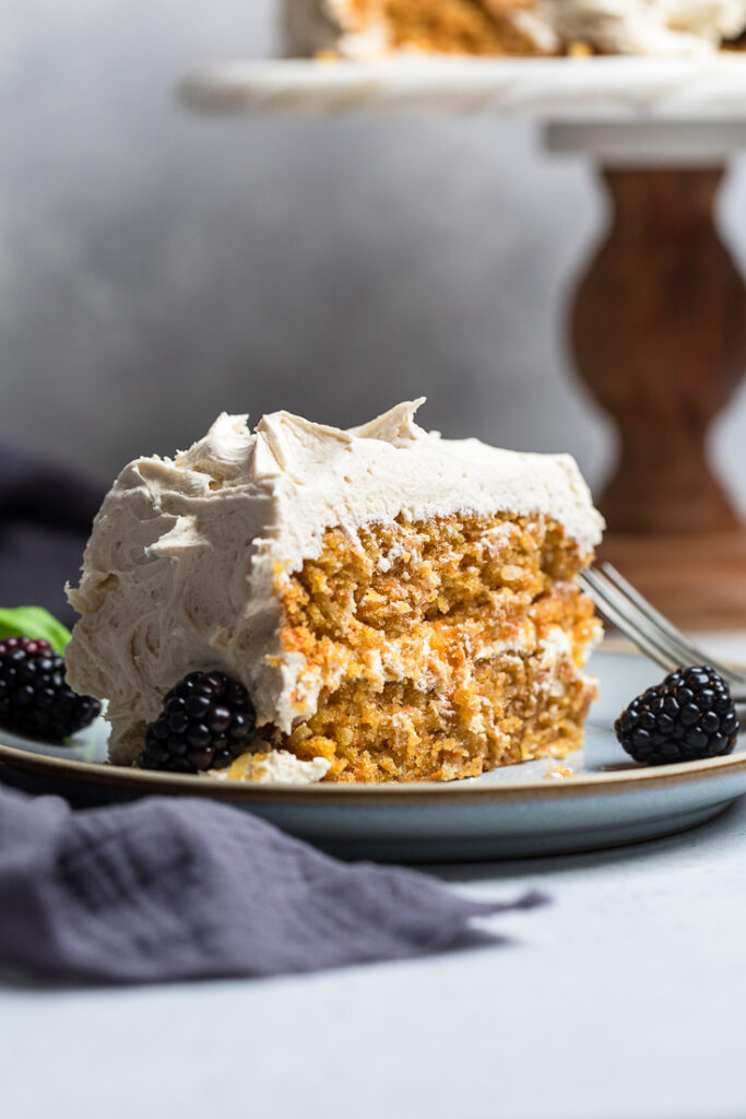 A slice of double layer Vegan coconut carrot cake with frosting on top.