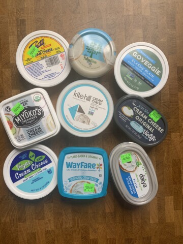 An assortment of vegan cream cheese products on a wooden table.