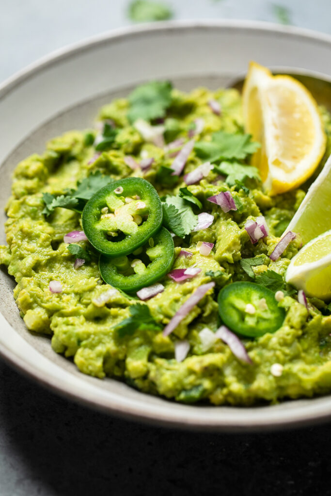 A bowl of copycat chipotle guacamole with fresh jalapenos and red onion. 
