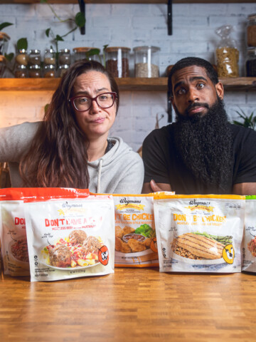 A couple posing behind an assortment of Wegman's meat substitute options making funny faces.