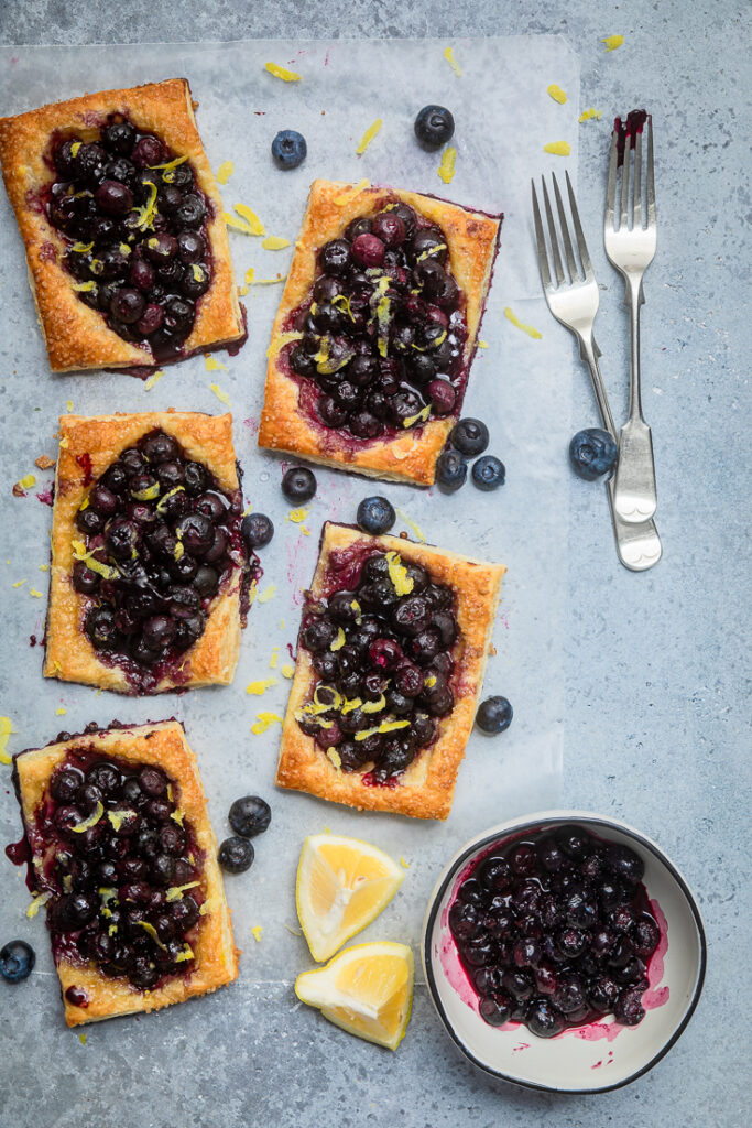 Five blueberry fruit tarts spread across a table.