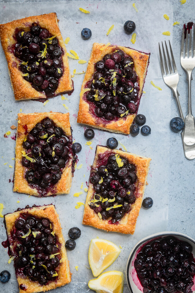 Freshly baked blueberry fruit tarts spread across a table.