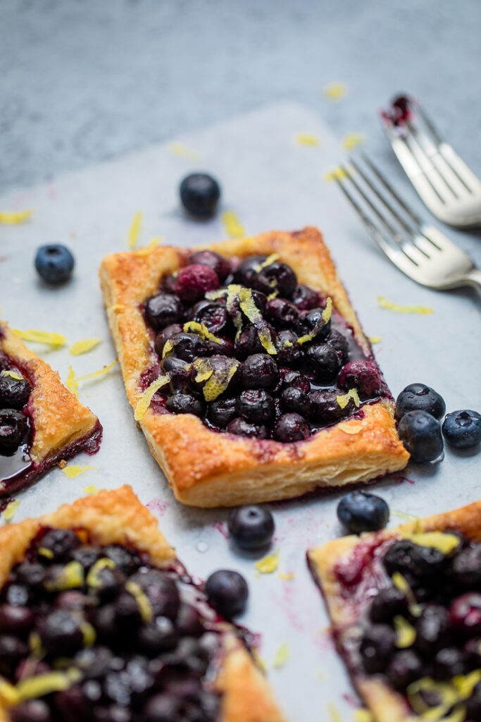 A vegan blueberry fruit tart freshly baked with fresh blueberries around.