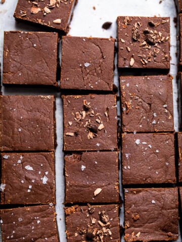 Tray of No Bake Vegan Chocolate Fudge cut into squares with flakey salt and chocolate shavings.