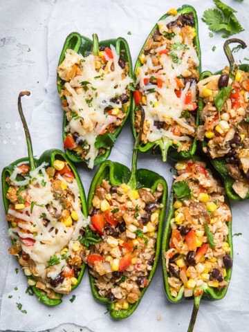 A table with six grilled vegan stuffed poblano peppers halved and cooked.